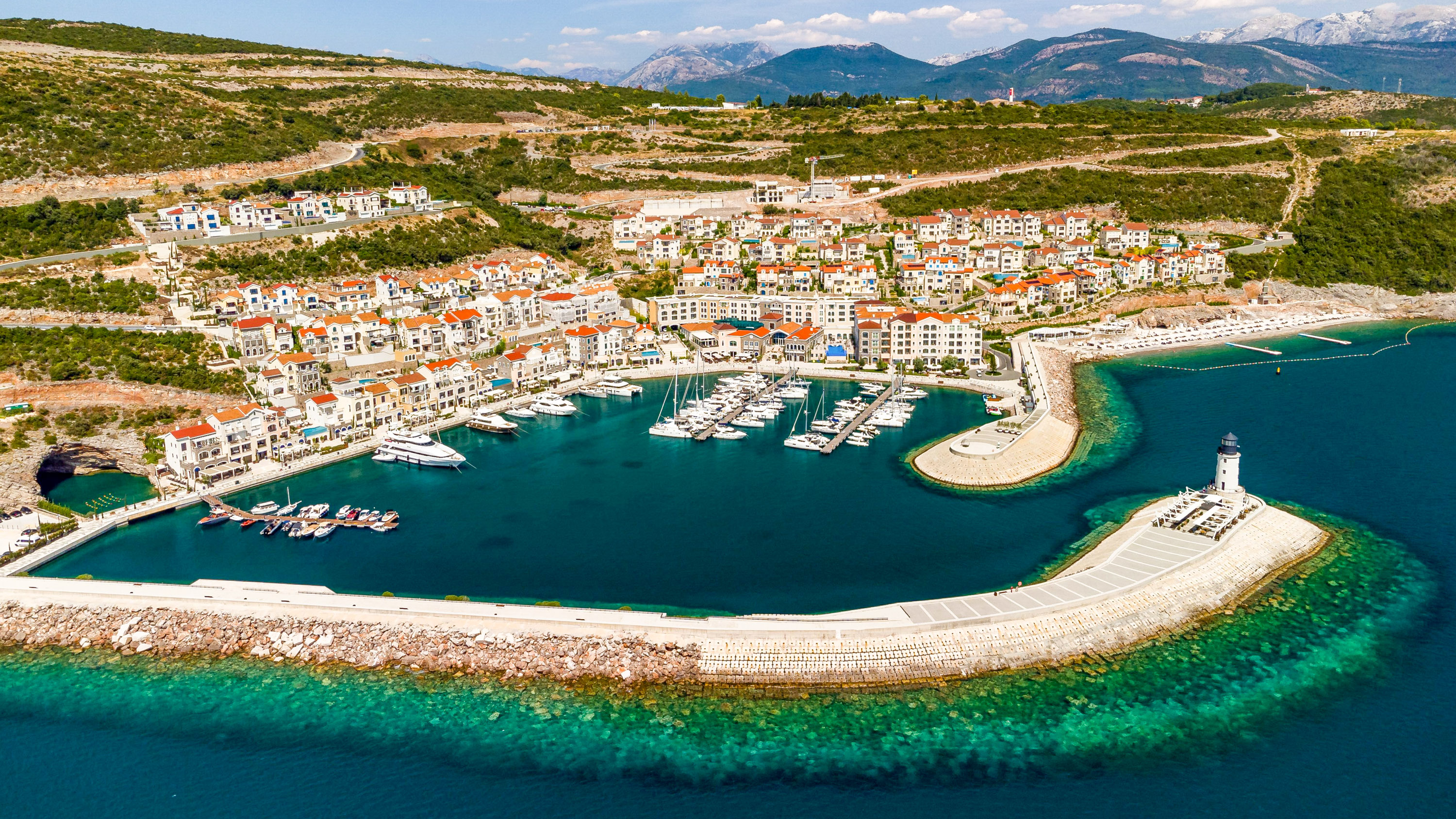 A high-angle drone shot of Lustica bay resort with forested mountains in the background