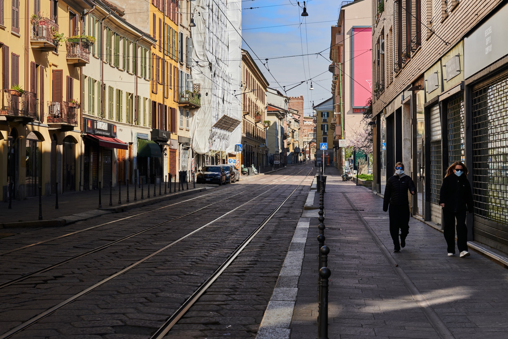 Two people wearing masks walk on the streets of Italy during the coronavirus pandemic.