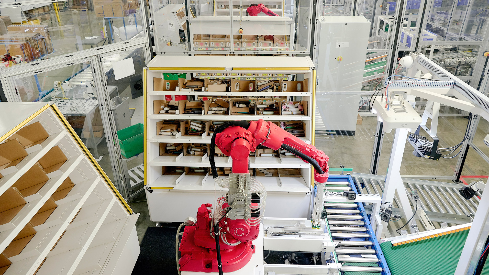 robotic arm moving objects between a conveyor belt and cubbies that surround its work space